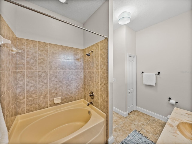 bathroom with tiled shower / bath combo, tile patterned flooring, vanity, and a textured ceiling