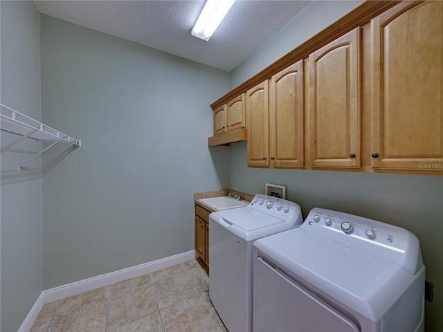 washroom featuring a textured ceiling, washing machine and dryer, light tile patterned floors, sink, and cabinets