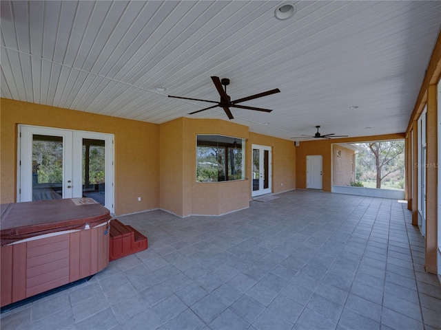 unfurnished sunroom featuring ceiling fan and french doors