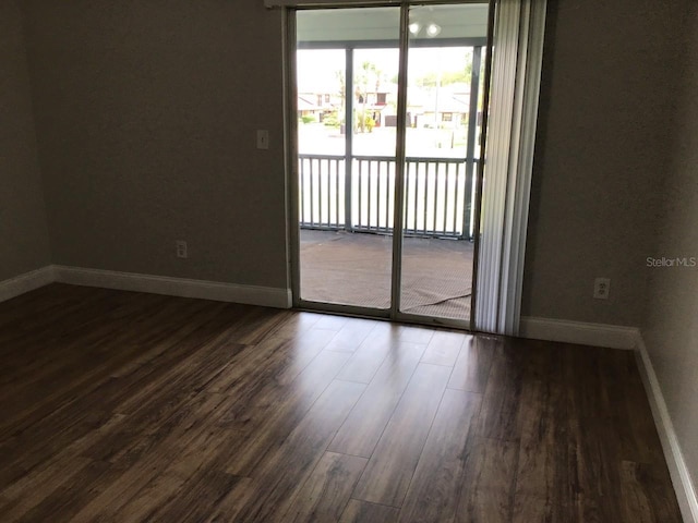 empty room with dark wood-type flooring and baseboards