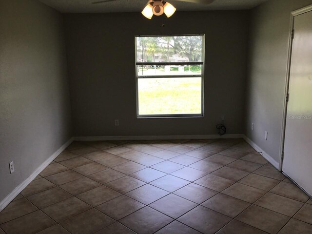 spare room featuring light tile patterned flooring, a ceiling fan, and baseboards