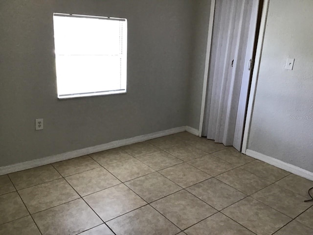 unfurnished bedroom featuring light tile patterned floors, a closet, and baseboards