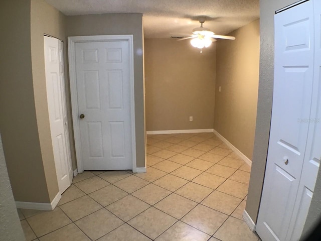 spare room featuring light tile patterned floors, ceiling fan, baseboards, and a textured ceiling