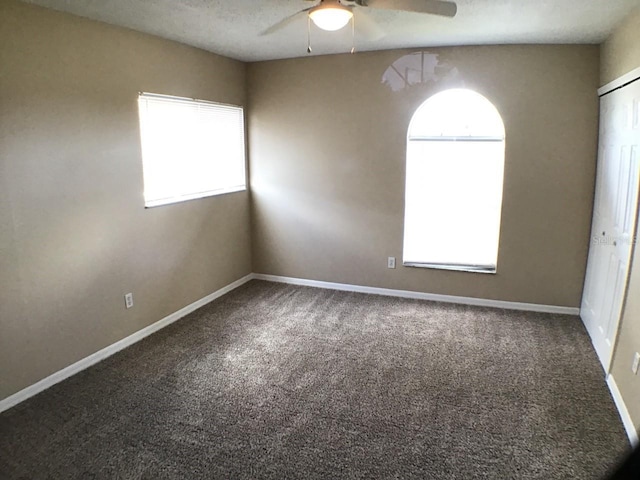 carpeted spare room with baseboards, ceiling fan, and a healthy amount of sunlight