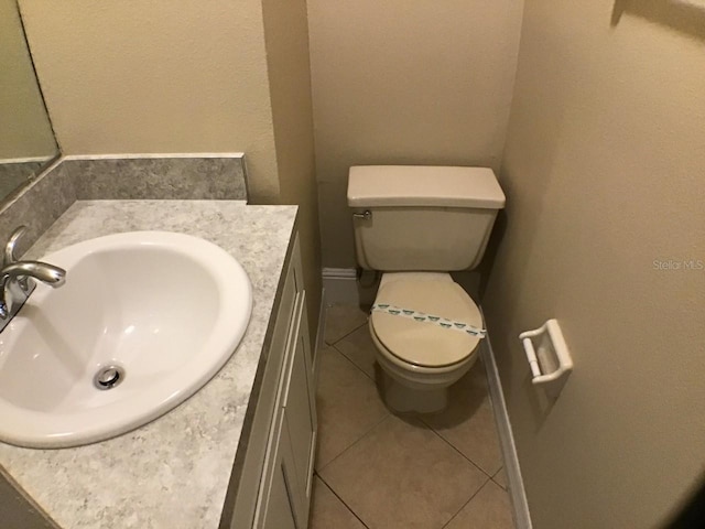 bathroom featuring toilet, tile patterned floors, baseboards, and vanity