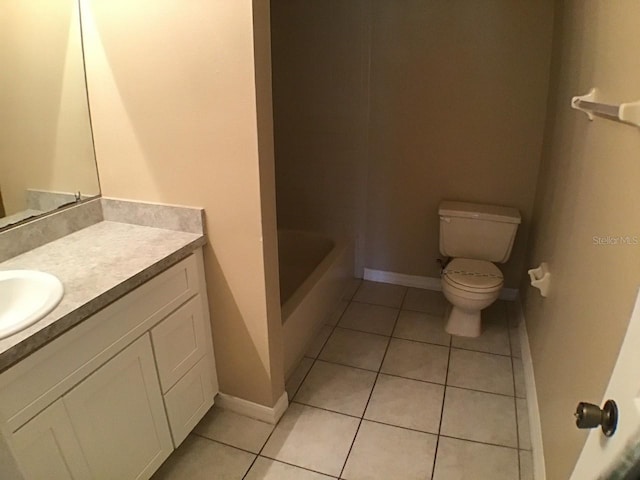 bathroom featuring toilet, tile patterned flooring, a tub to relax in, and vanity