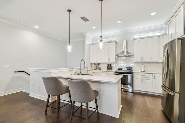 kitchen featuring white cabinetry, sink, appliances with stainless steel finishes, wall chimney exhaust hood, and pendant lighting