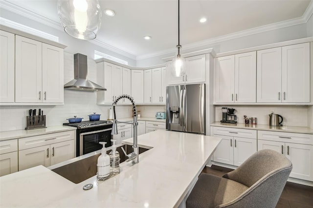 kitchen with hanging light fixtures, appliances with stainless steel finishes, wall chimney range hood, crown molding, and a breakfast bar area