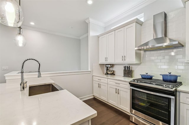 kitchen with decorative light fixtures, white cabinets, wall chimney range hood, and stainless steel gas range oven