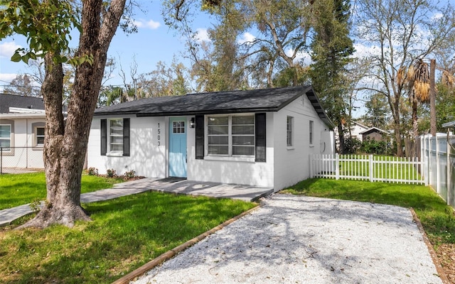 view of front facade featuring concrete block siding, a front lawn, and fence