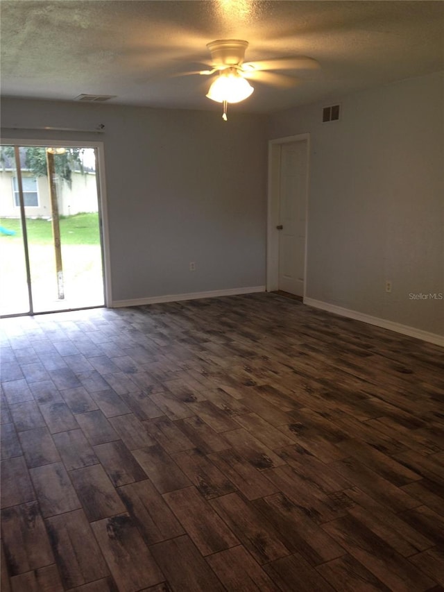 spare room with dark wood-type flooring, visible vents, a textured ceiling, and baseboards