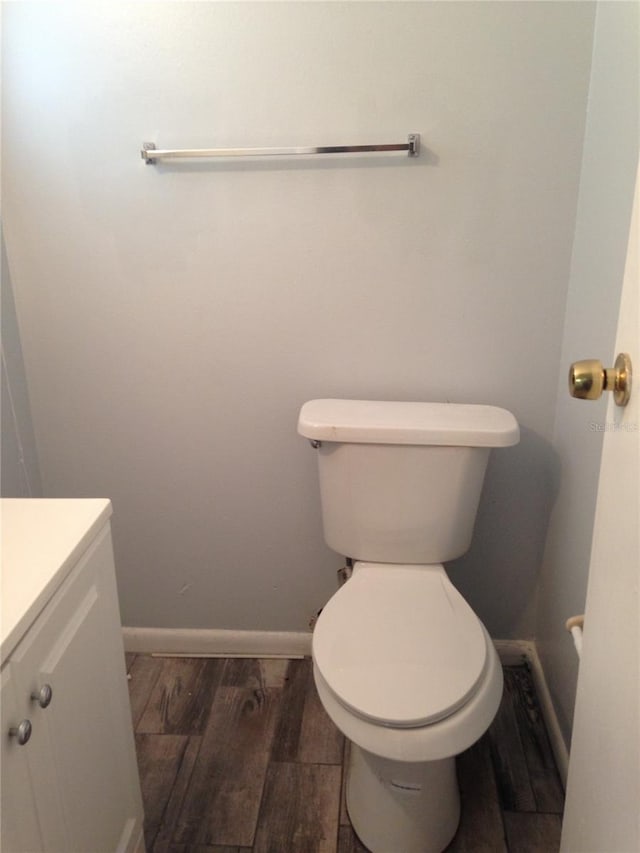 bathroom featuring toilet, vanity, baseboards, and wood finished floors