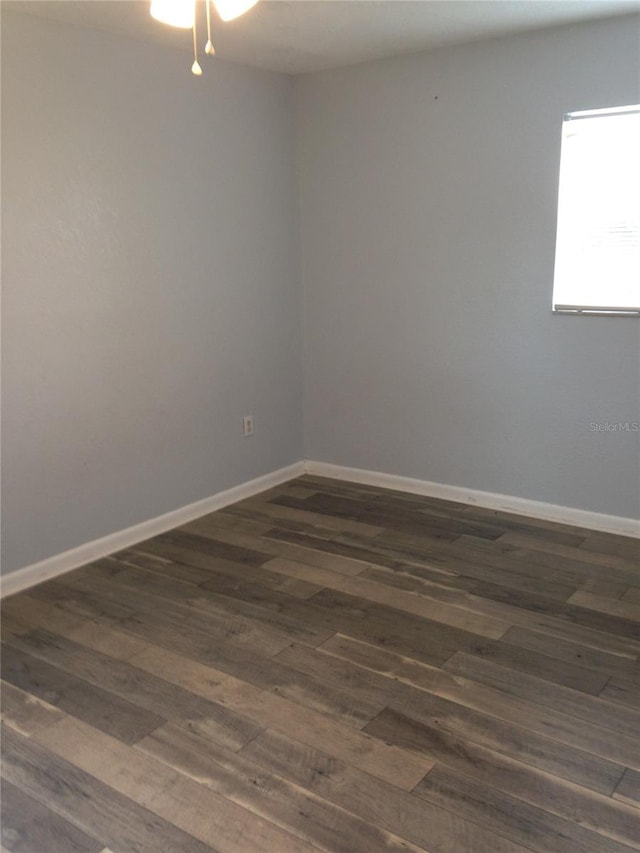 spare room featuring dark wood-style floors and baseboards