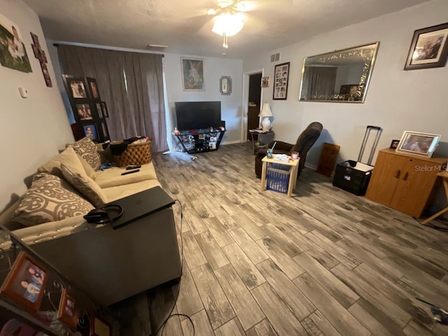 living area featuring a ceiling fan, visible vents, and wood finished floors