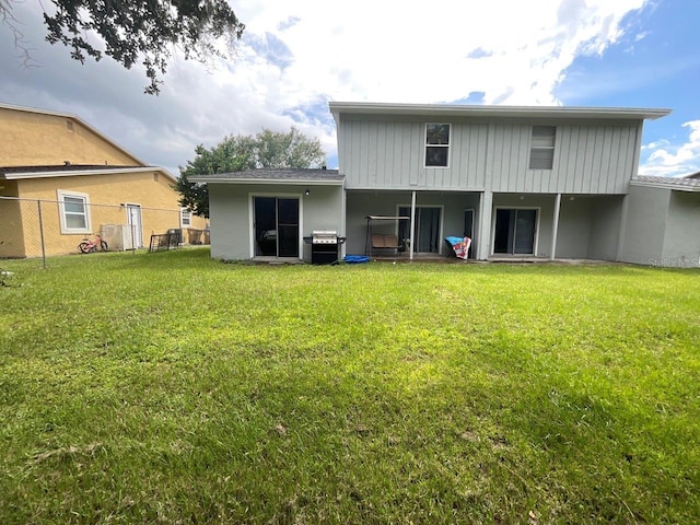 back of property with fence and a yard