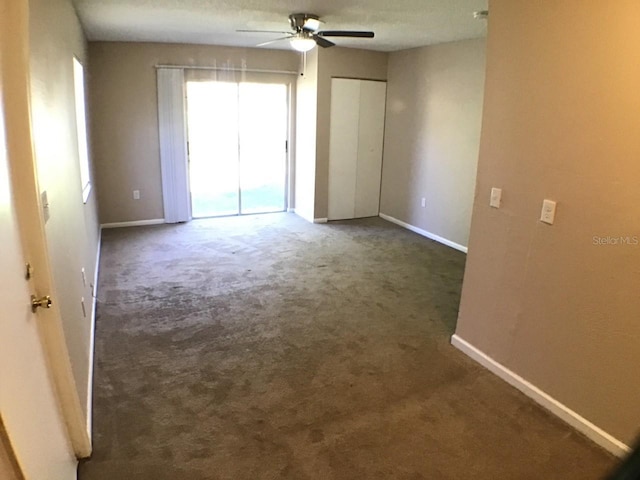 unfurnished room featuring dark colored carpet, ceiling fan, and baseboards