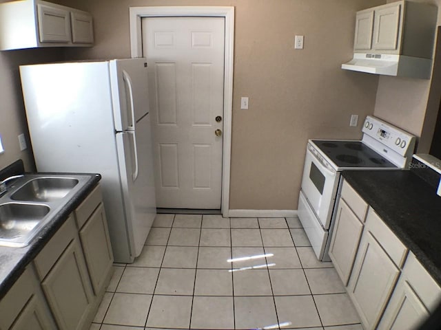 kitchen with white appliances, light tile patterned floors, dark countertops, under cabinet range hood, and a sink