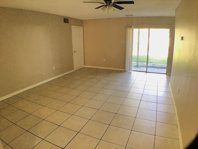 empty room with light tile patterned floors, ceiling fan, visible vents, and baseboards