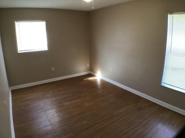 spare room featuring ceiling fan, dark wood-style flooring, and baseboards