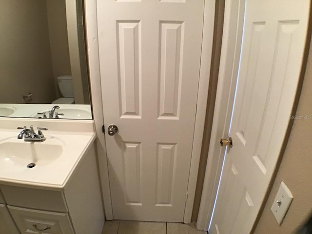 half bathroom with a sink, toilet, and tile patterned floors