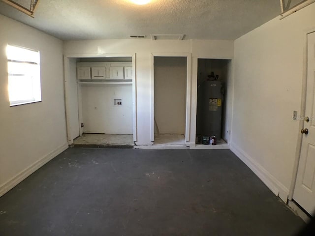 interior space featuring two closets, visible vents, water heater, a textured ceiling, and baseboards