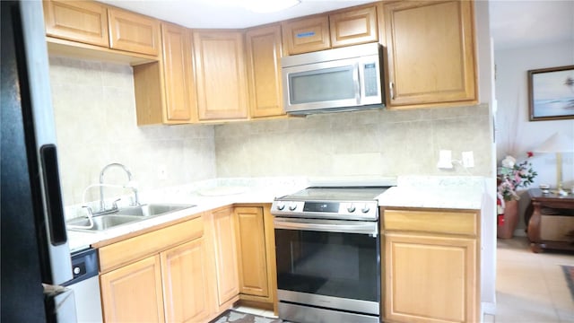 kitchen featuring sink, backsplash, appliances with stainless steel finishes, and light brown cabinetry