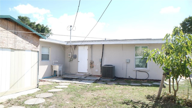 back of property with a lawn and central AC