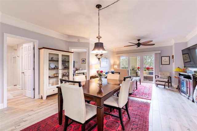 dining space featuring light wood-style flooring, ornamental molding, and ceiling fan