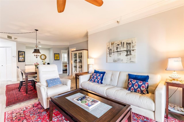 living room featuring baseboards, a ceiling fan, and crown molding