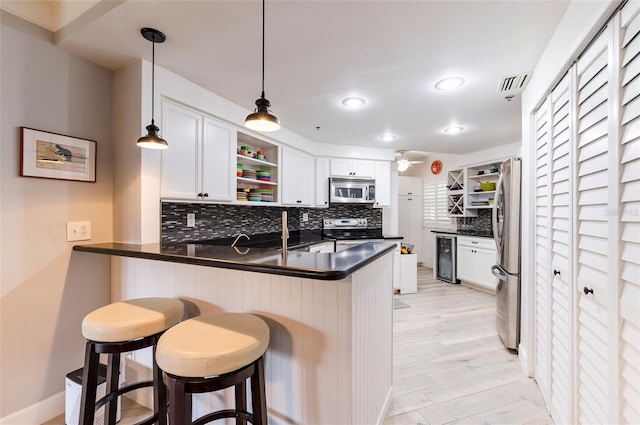 kitchen featuring open shelves, a peninsula, a kitchen bar, and stainless steel appliances