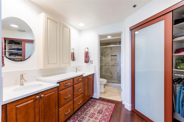 bathroom featuring a spacious closet, toilet, a stall shower, vanity, and wood finished floors