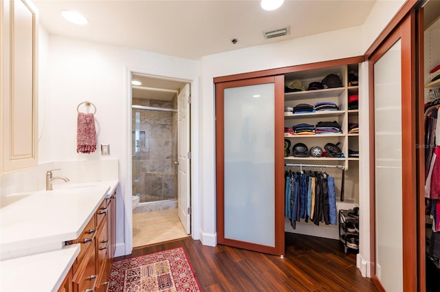 bathroom with visible vents, wood finished floors, a walk in closet, vanity, and a shower stall