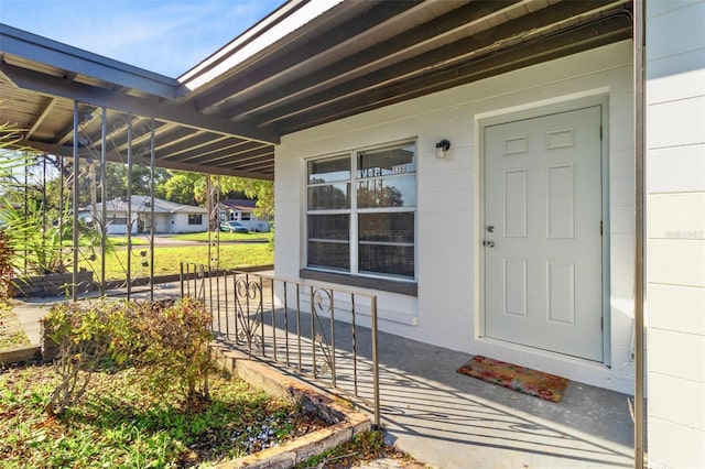 property entrance with a porch, an attached carport, and concrete block siding