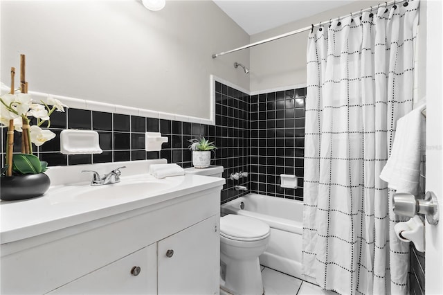 bathroom with toilet, a wainscoted wall, shower / bathtub combination with curtain, vanity, and tile walls