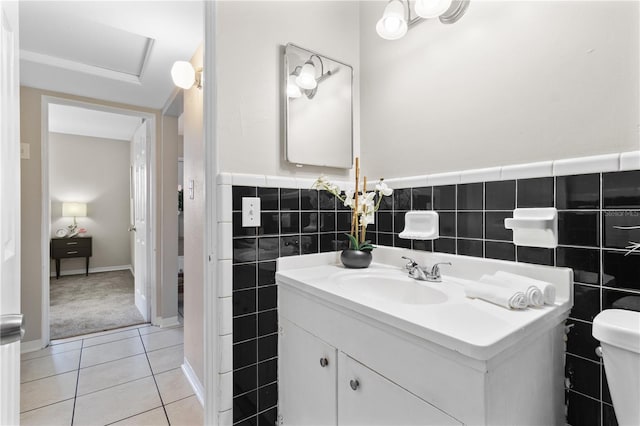 bathroom featuring toilet, a wainscoted wall, tile patterned flooring, vanity, and tile walls