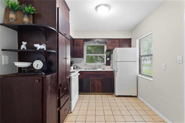 kitchen with light tile patterned floors, electric range oven, freestanding refrigerator, light countertops, and a sink