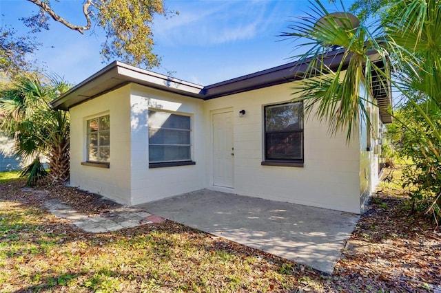 view of front of property featuring a patio and concrete block siding