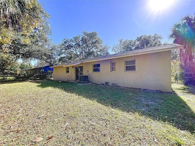 back of house with a yard, central AC unit, and stucco siding