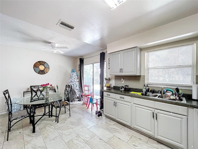 kitchen featuring dark countertops, visible vents, backsplash, ceiling fan, and a textured ceiling