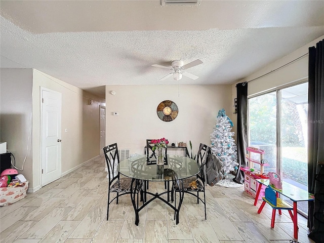 dining space featuring baseboards, a ceiling fan, and a textured ceiling