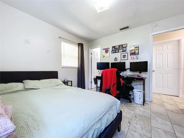 bedroom with a textured ceiling, marble finish floor, and visible vents