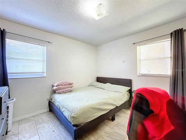 bedroom featuring baseboards and a textured ceiling