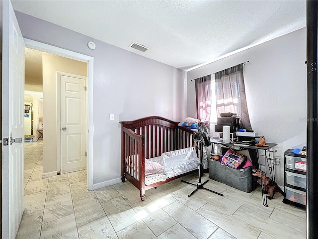 bedroom featuring baseboards, visible vents, and a textured ceiling