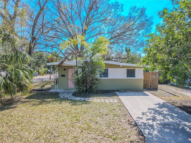 view of front of house with fence, a front lawn, and stucco siding