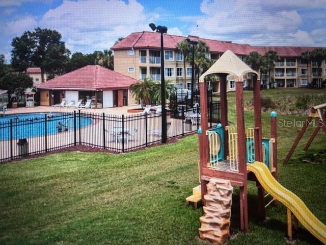 view of jungle gym with a yard and a community pool