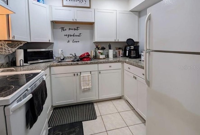 kitchen with light tile patterned flooring, white appliances, and white cabinets