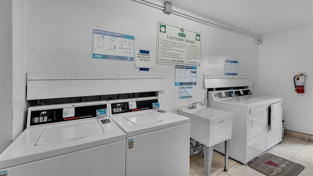 clothes washing area featuring light tile patterned floors, sink, and separate washer and dryer