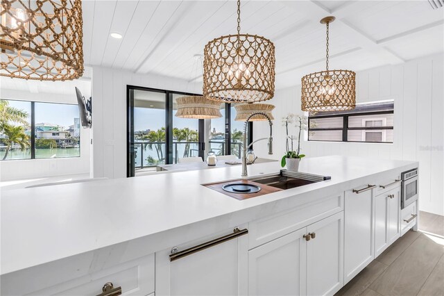 8505 Blind Pass Dr, Treasure Island, FL 33706 - kitchen featuring a sink, light countertops, a chandelier, white cabinets, and pendant lighting