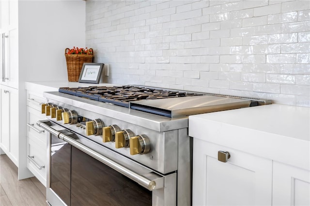 8505 Blind Pass Dr, Treasure Island, FL 33706 - kitchen featuring double oven range, decorative backsplash, white cabinetry, and light countertops