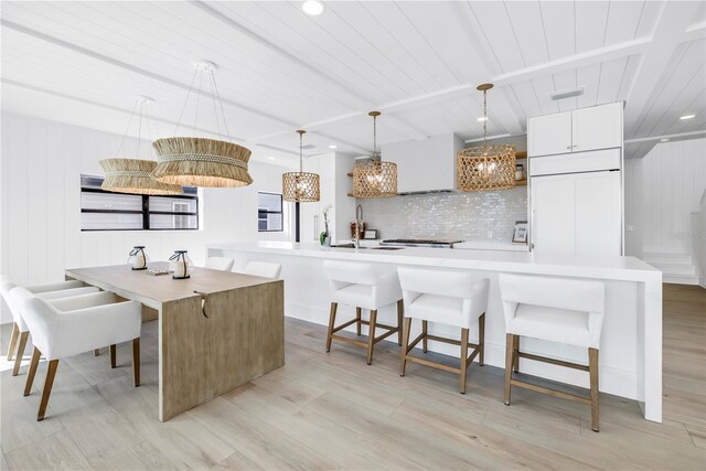 8505 Blind Pass Dr, Treasure Island, FL 33706 - kitchen featuring backsplash, light wood-style floors, a sink, a kitchen breakfast bar, and pendant lighting